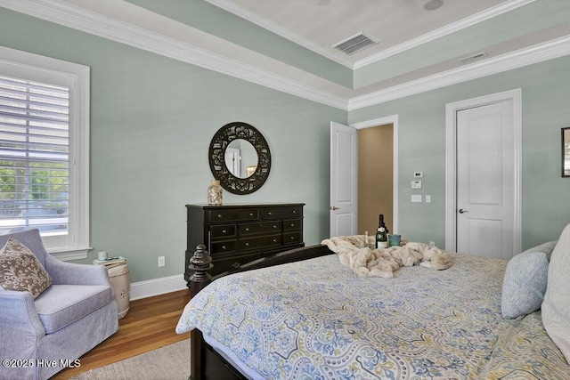 bedroom with baseboards, visible vents, multiple windows, and wood finished floors