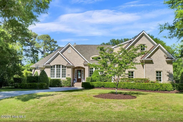 view of front of house with a chimney, a front lawn, and brick siding