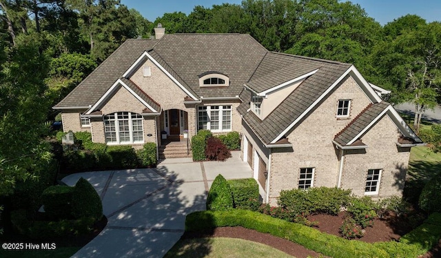 view of front of house featuring concrete driveway, brick siding, and a chimney