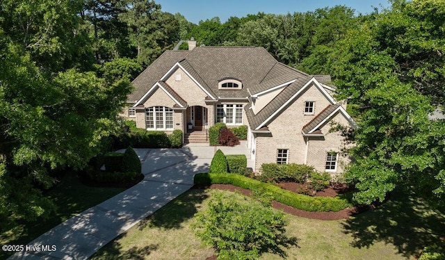 view of front of home with a chimney and brick siding