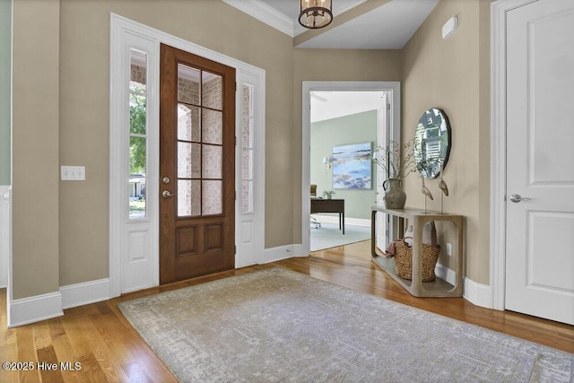 entrance foyer featuring baseboards, crown molding, and wood finished floors