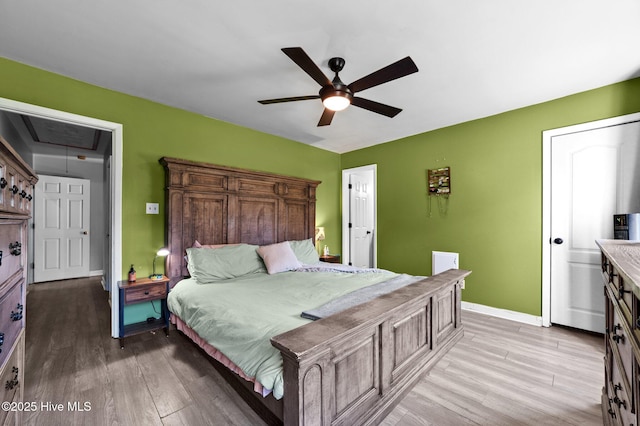 bedroom featuring attic access, baseboards, a ceiling fan, and light wood-style floors