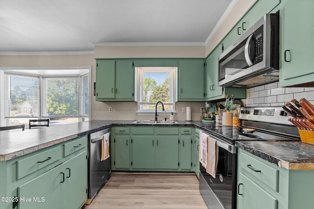 kitchen with a peninsula, a sink, appliances with stainless steel finishes, and crown molding