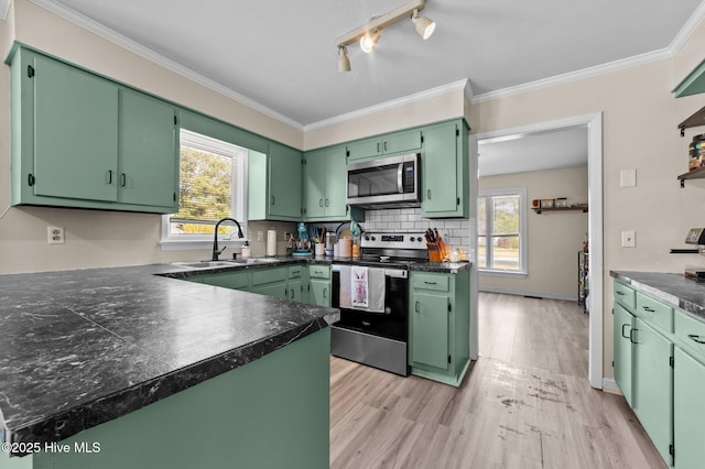 kitchen featuring light wood-type flooring, stainless steel appliances, decorative backsplash, and a sink