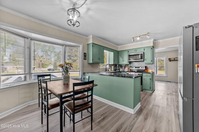 kitchen featuring ornamental molding, a peninsula, green cabinetry, and appliances with stainless steel finishes