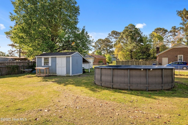 view of yard featuring an outdoor structure, a storage unit, a fenced in pool, and a fenced backyard