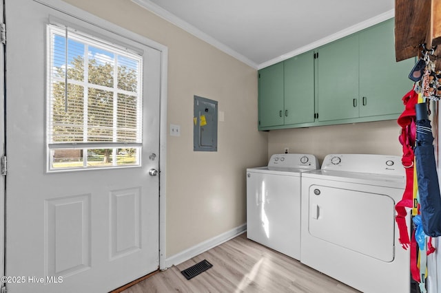 laundry room featuring washer and clothes dryer, ornamental molding, light wood-style floors, electric panel, and cabinet space