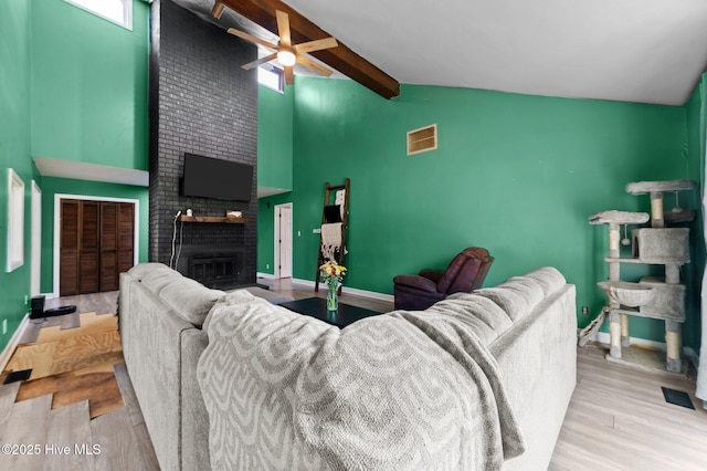 living area with beam ceiling, baseboards, visible vents, a brick fireplace, and high vaulted ceiling