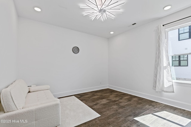 unfurnished room featuring dark wood-type flooring, visible vents, and baseboards