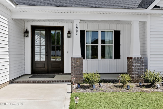 view of exterior entry with board and batten siding, french doors, and roof with shingles