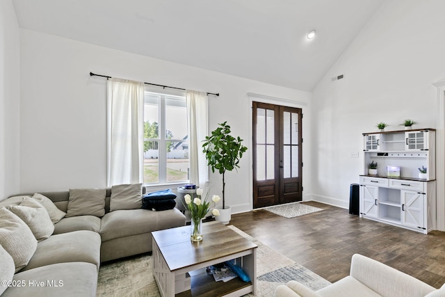 living area with french doors, visible vents, baseboards, wood finished floors, and high vaulted ceiling