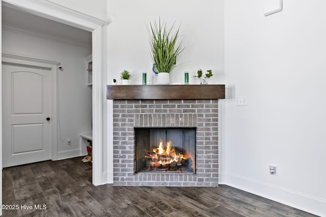 interior details with baseboards, crown molding, a brick fireplace, and wood finished floors