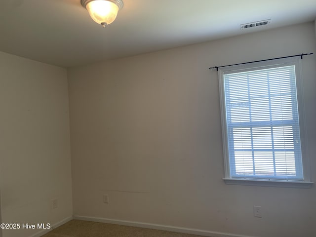 spare room with carpet floors, baseboards, and visible vents