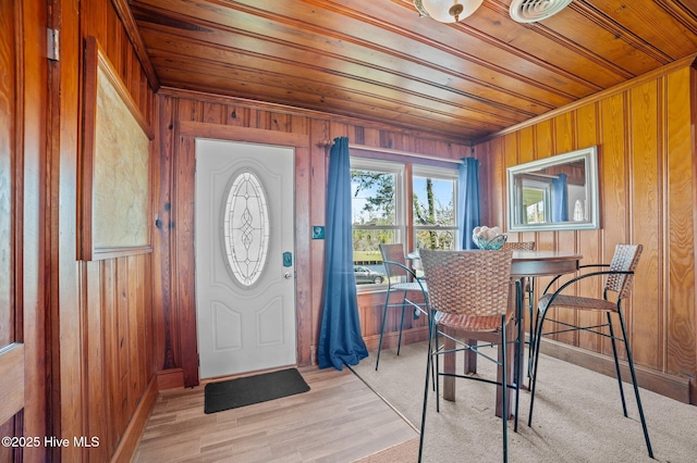 entrance foyer featuring wood ceiling, wooden walls, baseboards, and light wood-style floors