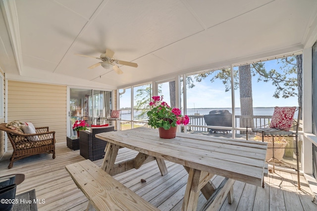 sunroom / solarium featuring outdoor lounge area, a ceiling fan, outdoor dining area, and a water view