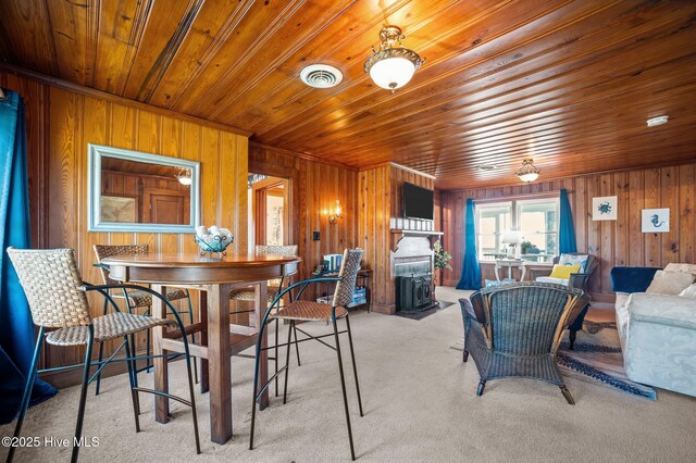 dining space with wooden walls, visible vents, wood ceiling, and light colored carpet