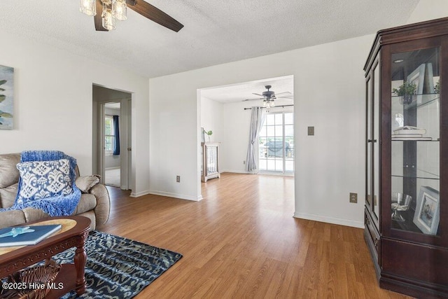living room with wood finished floors, baseboards, and ceiling fan
