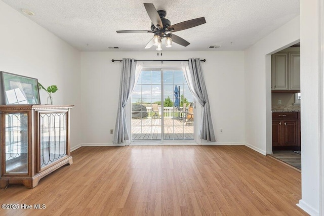 unfurnished living room with baseboards, visible vents, a textured ceiling, and light wood-style floors