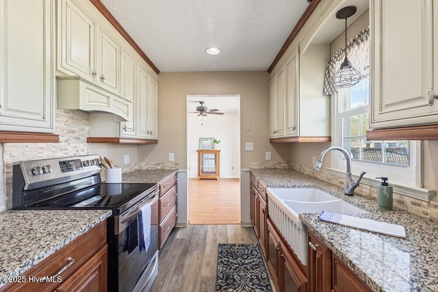 kitchen with a ceiling fan, wood finished floors, a textured ceiling, stainless steel electric stove, and backsplash
