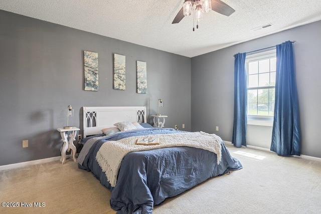 bedroom featuring light carpet, a textured ceiling, visible vents, and baseboards