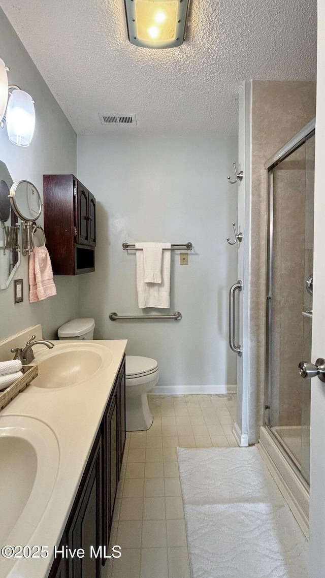 bathroom featuring a textured ceiling, a shower stall, visible vents, and a sink