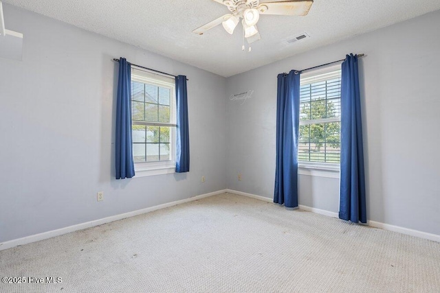 empty room with a textured ceiling, ceiling fan, carpet floors, baseboards, and visible vents