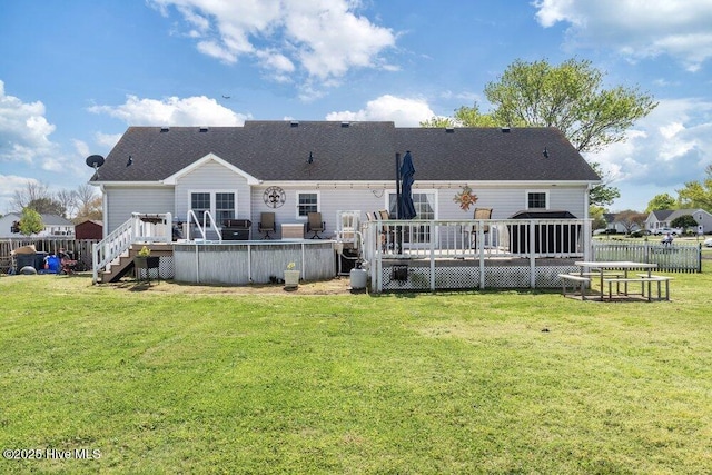 rear view of house with fence, a lawn, roof with shingles, and a deck