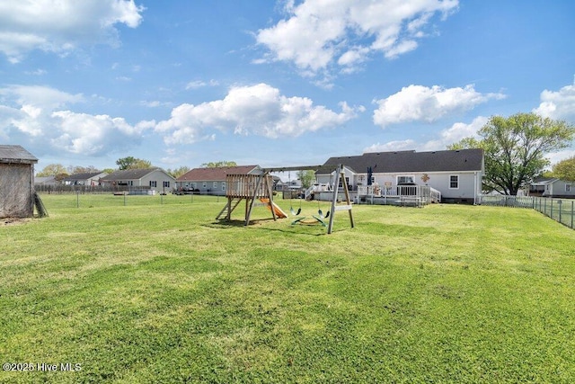 view of yard featuring fence, a deck, and a playground