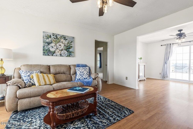 living area with baseboards, a ceiling fan, and wood finished floors