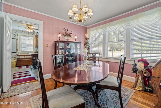 dining space with ceiling fan with notable chandelier, crown molding, wood finished floors, and plenty of natural light