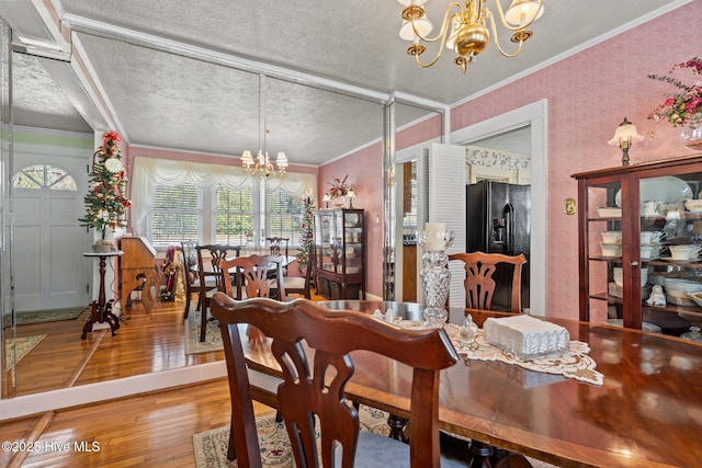 dining space with ornamental molding, a notable chandelier, hardwood / wood-style floors, and a textured ceiling