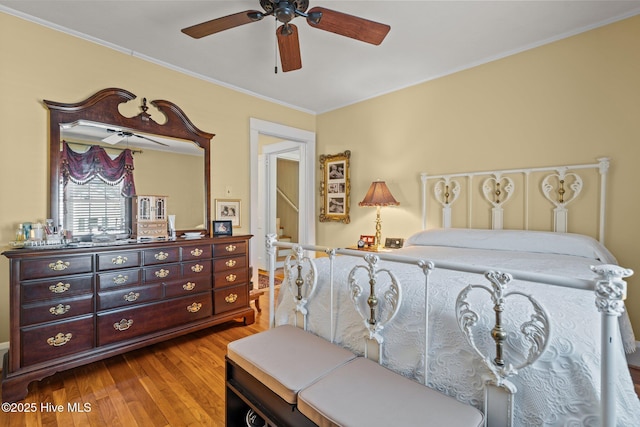 bedroom with a ceiling fan, wood finished floors, and ornamental molding
