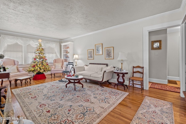 living room featuring wood finished floors, a textured ceiling, and ornamental molding