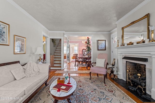 living area with stairs, crown molding, wood finished floors, and a textured ceiling