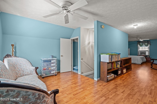 sitting room featuring lofted ceiling, a ceiling fan, wood finished floors, and a textured ceiling