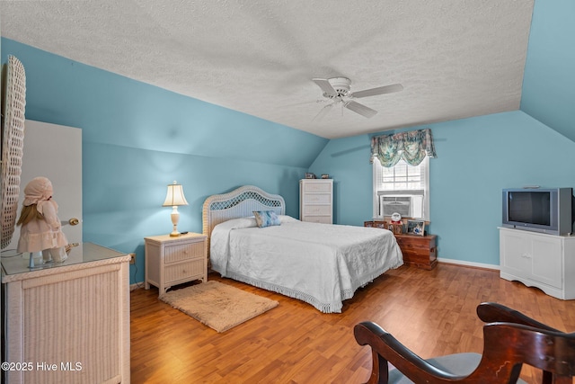 bedroom featuring lofted ceiling, cooling unit, wood finished floors, and a textured ceiling
