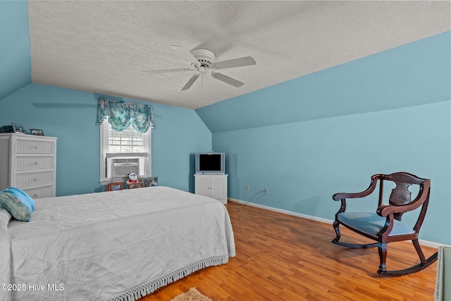 bedroom with vaulted ceiling, wood finished floors, cooling unit, and a textured ceiling