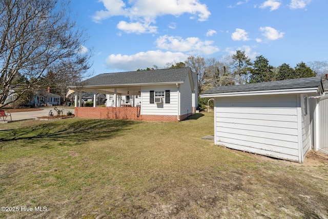 back of property with a shingled roof, an outdoor structure, covered porch, and a yard