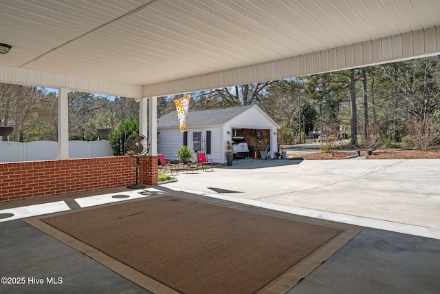 view of patio / terrace featuring an outdoor structure, concrete driveway, a garage, and fence