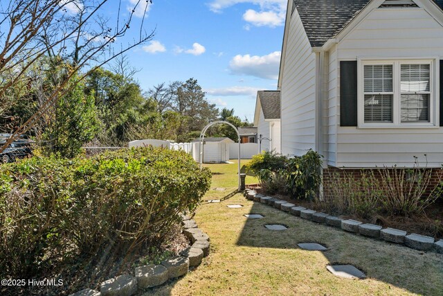view of yard with fence, an outbuilding, and a storage shed