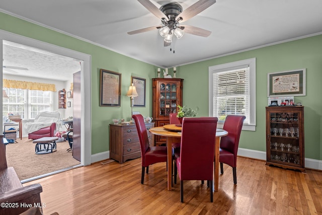 dining area featuring baseboards, a ceiling fan, wood finished floors, and ornamental molding