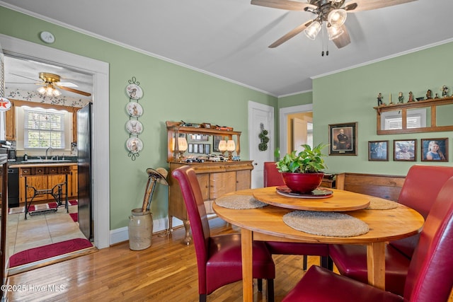 dining room featuring light wood finished floors, ornamental molding, and ceiling fan