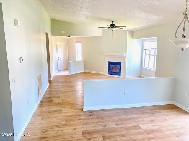 4105 Breezwood Dr Unit 203, Wilmington, NC 28412 - unfurnished living room featuring a textured ceiling, ceiling fan, light wood-style floors, a tile fireplace, and baseboards