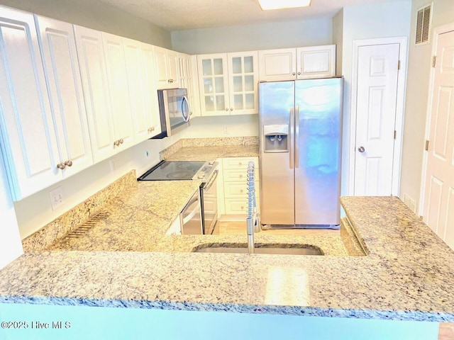 4105 Breezwood Dr Unit 203, Wilmington, NC 28412 - kitchen with stainless steel appliances, light stone counters, glass insert cabinets, and white cabinets