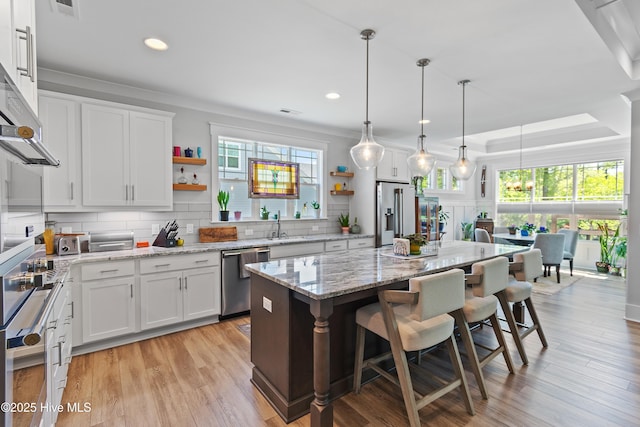 3981 Bay Colony Rd NE, Leland, NC 28451 - kitchen with appliances with stainless steel finishes, open shelves, tasteful backsplash, a breakfast bar, and white cabinets