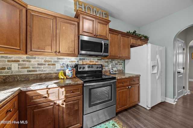 259 Luther Banks Rd, Richlands, NC 28574 - kitchen with dark wood-style floors, arched walkways, dark countertops, brown cabinets, and appliances with stainless steel finishes