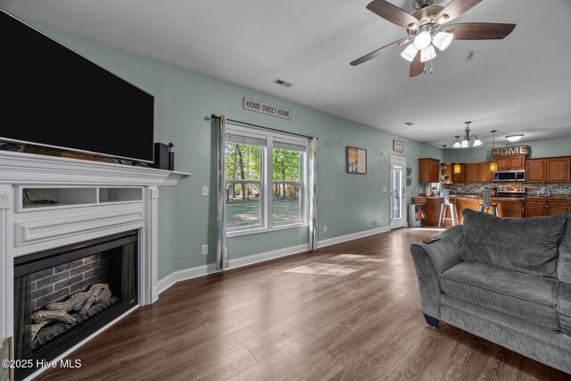 259 Luther Banks Rd, Richlands, NC 28574 - living area with baseboards, visible vents, ceiling fan with notable chandelier, a fireplace, and dark wood-type flooring