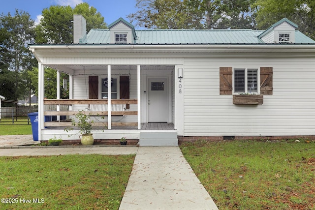 view of front of house with a porch, a front yard, and metal roof