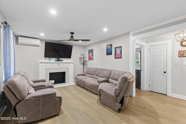 living room with light wood-type flooring, recessed lighting, a fireplace with raised hearth, ceiling fan, and a wall mounted AC