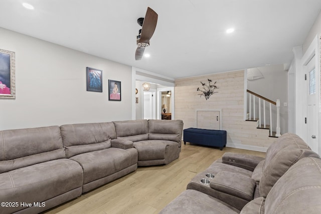 living area with recessed lighting, wooden walls, stairway, and wood finished floors